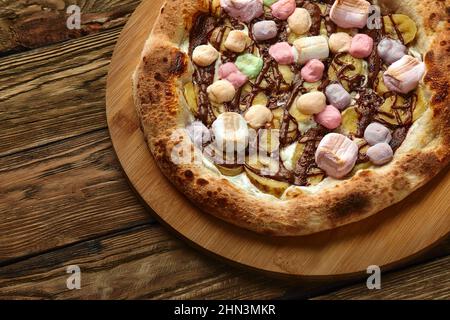 Pizza dolce intera servita con marshmallows e caramelle su sfondo di legno Foto Stock