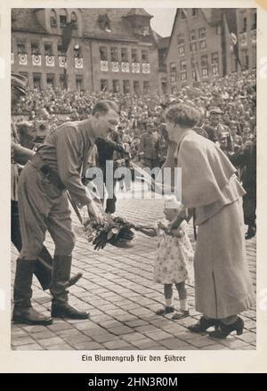 Cartolina della propaganda tedesca d'epoca: Una bambina passa un bouquet di fiori ad Adolf Hitler. 1930s solo per i purpope storici! Foto Stock