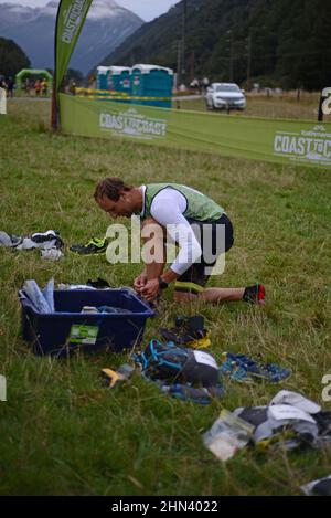 AICKENS, NUOVA ZELANDA, 12 FEBBRAIO 2022; Un concorrente prepara il suo equipaggiamento al punto di passaggio per la sezione di corsa di montagna 33km del Triathlon da Costa a Costa Foto Stock