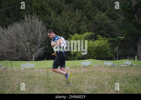 AICKENS, NUOVA ZELANDA, 12 FEBBRAIO 2022; Un concorrente prepara il suo equipaggiamento al punto di passaggio per la sezione di corsa di montagna 33km del Triathlon da Costa a Costa Foto Stock