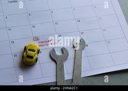 Concetto di manutenzione programmata del veicolo. Auto giocattolo, chiave e calendario con testo MANUTENZIONE PROGRAMMATA Foto Stock