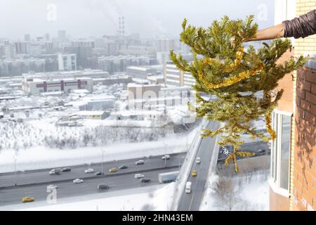 Concepiscono la fine delle vacanze e delle celebrazioni. Uomo gettando via albero felluto dalla sua casa dopo Natale e Capodanno. Albero secco appassito Foto Stock