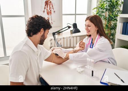 L'uomo e la donna che indossano l'uniforme del medico che hanno analisi del sangue in clinica Foto Stock