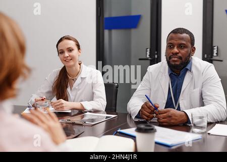 Due giovani esperti interculturali di assistenza sanitaria in laboratori di consulenza colleghi su domande frequenti riguardanti la pandemia Foto Stock