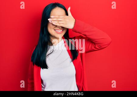 Bella donna ispanica con naso piercing indossando look casual e occhiali sorridenti e ridenti con mano sul viso occhi di copertura per sorpresa. Cieco c Foto Stock