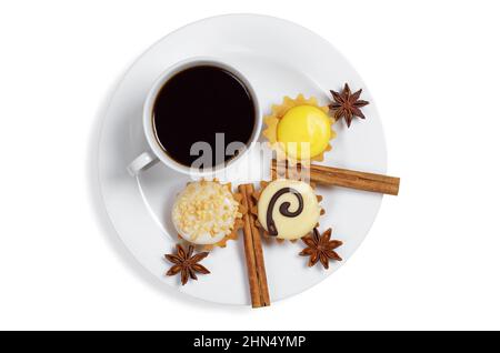 Piatto con tazza di caffè, vari cupcake glassati, bastoncini di cannella e stella anice su sfondo bianco, vista dall'alto Foto Stock