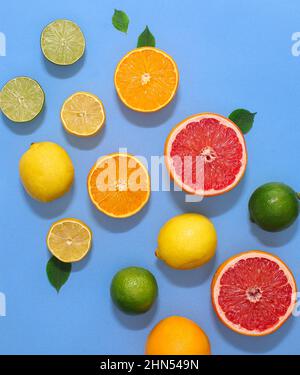 Composizione estiva di diversi agrumi disposti su sfondo blu pastello. Disposizione piatta Foto Stock