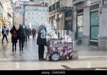 Lisbona, Portogallo - 12 25 2018: Venditore di strada che vende castagne arrostite durante l'inverno con turisti che camminano sullo sfondo intorno a Piazza Rossio Foto Stock