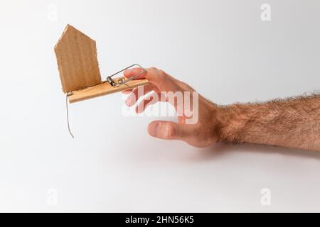 Concetto di investimenti e rischi bancari. La mano di un uomo cade in un mousetrap, con un cartone. Spazio di copia. Foto Stock