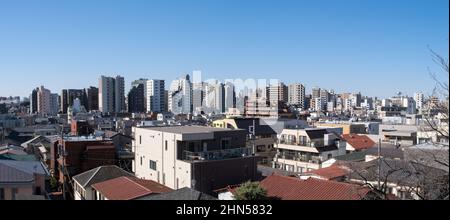 Una vista del paesaggio urbano di tarda mattinata del Ward di Arakawa a Tokyo con case in primo piano e grattacieli Foto Stock