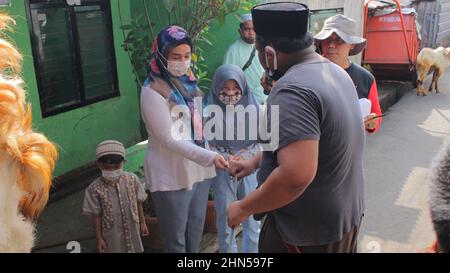 Giacarta, Indonesia - 07-31-2020: Una madre e diversi bambini si stringono le mani con uno degli organizzatori qurban per il permesso di fare qabul su Eid al-Adha Foto Stock