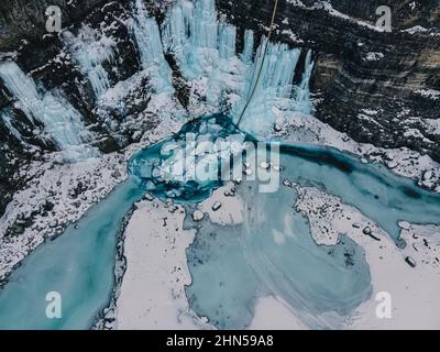 Parete ghiacciata su muro di roccia che conduce in piscina di acqua ghiacciata Foto Stock