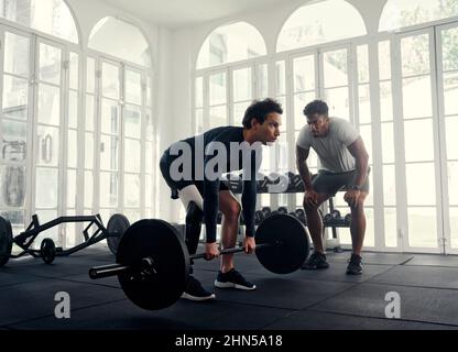 L'atleta disabili che solleva il peso con il suo allenatore in palestra. Uomo con gamba protesica che viene allenato dal suo istruttore Foto Stock