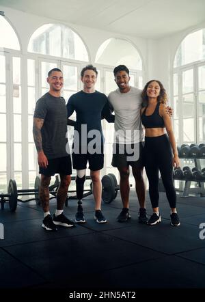 Gruppo di amici diversi che si allenano in una palestra moderna. Ritratto di un gruppo di amici multirazziali che sorride alla fotocamera Foto Stock