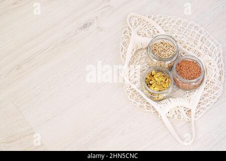 Semi organici in un negozio di rifiuti zero. Lino, girasole e semi di zucca in vasetti di vetro su sfondo di legno. Shopping ecologico. Spazio di copia. Foto Stock