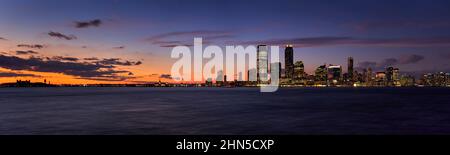 Grattacieli del centro di Jersey City dopo il tramonto. Vista sul fiume Hudon al crepuscolo da Ellis Island a Newport, New Jersey Foto Stock