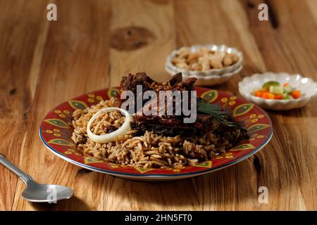 Nasi Kebuli (riso Kabuli), Arabo o India Pilaf con costolette di manzo o agnello, su tavola di legno Foto Stock