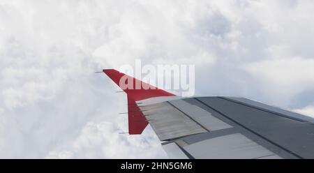 Ala di un aereo che vola sopra la città. La vista da una finestra aereo. Cielo nuvoloso e colorato con luce solare. Foto applicata agli operatori turistici. T Foto Stock