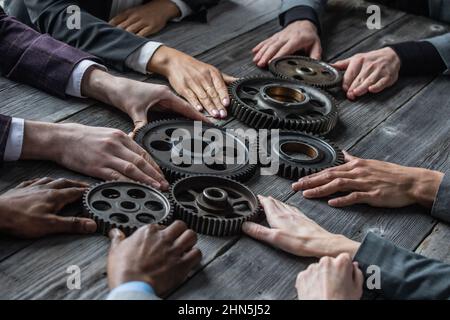 Gruppo di uomini d'affari che uniscono gli ingranaggi sul tavolo sul posto di lavoro Foto Stock