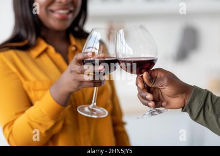 Grazie. Primo piano Shot della giovane coppia afroamericana che beve vino, bicchieri clinking Foto Stock