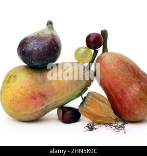 Assortimento fresco di frutta, tra cui pere, fichi e uva, disposti esteticamente su sfondo bianco Foto Stock