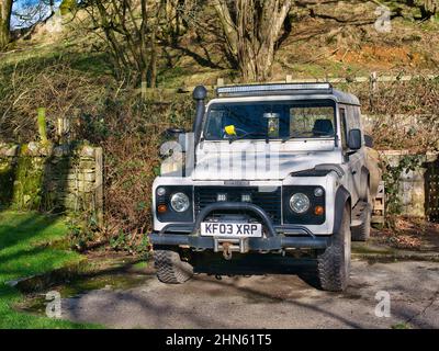 Un Land Rover Defender 2003 bianco dotato di verricello, presa d'aria e illuminazione a LED. In una giornata di sole d'inverno. Foto Stock