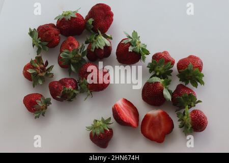 Fragole fresche. Piccolo e grande. Combinazione rosa rossa e verde. Scatto su sfondo bianco Foto Stock