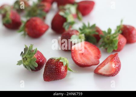 Fragole fresche. Piccolo e grande. Combinazione rosa rossa e verde. Scatto su sfondo bianco Foto Stock