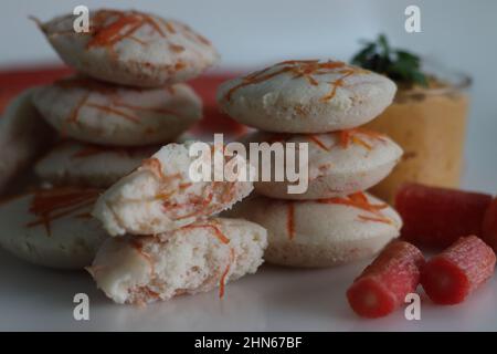 Carota folle e chutney di cocco. Torte di riso al vapore con carote grattugiate servite con condimenti piccanti al cocco. Scatto su sfondo bianco Foto Stock