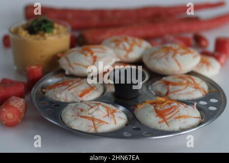 Carota folle e chutney di cocco. Torte di riso al vapore con carote grattugiate sparate con muffa folle. Servito con condimenti piccanti di cocco. Scatto sul retro bianco Foto Stock