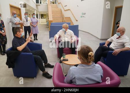 Il primo ministro Boris Johnson parla a David Miller (a sinistra), 63, che sta attraversando le fasi finali del suo trattamento chemioterapico, e John Stevenson (a destra), MP for Carlisle, durante una visita al Northern Center for Cancer Care, North Cumbria, a Carlisle, come parte del suo tour nel Regno Unito. Data foto: Lunedì 14 febbraio 2022. Foto Stock