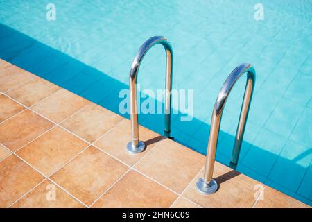 Scala di una piscina in una giornata estiva soleggiata Foto Stock