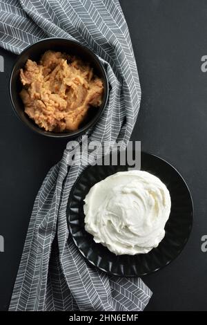 Tarama cruda su recipiente nero e taramosalata bianca su batella nera Foto Stock