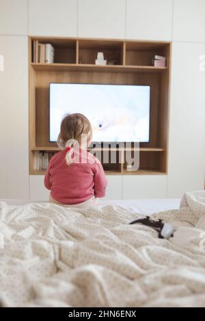 Piccola ragazza carina che guarda la televisione a casa. Foto Stock