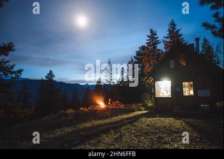 Seduti intorno ad un fuoco in una cabina in montagna Foto Stock