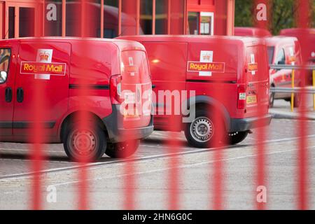 I furgoni di consegna Royal Mail parcheggiati presso l'ufficio di consegna di Huntingdon, Cambridgeshire in cortile dietro porte d'ingresso rosse chiuse Foto Stock