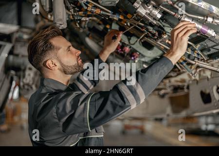 Tecnico di manutenzione maschile che ripara l'aeroplano in hangar Foto Stock