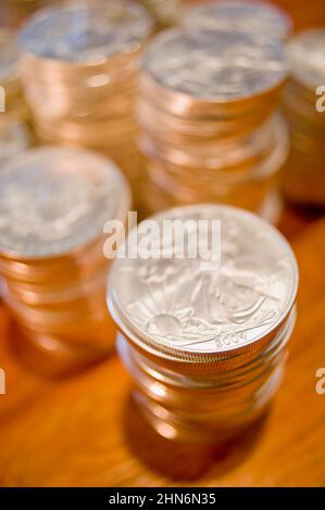 Pile di brillanti dollari della libertà d'argento si siedono su un caldo tavolo in legno Foto Stock