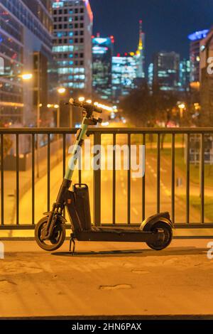 e-scooter sul ponte di fronte alla città di notte a francoforte principale, germania Foto Stock