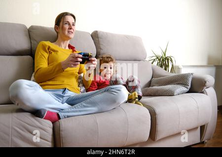 Madre e figlio concentrandosi durante la riproduzione di videogiochi Foto Stock
