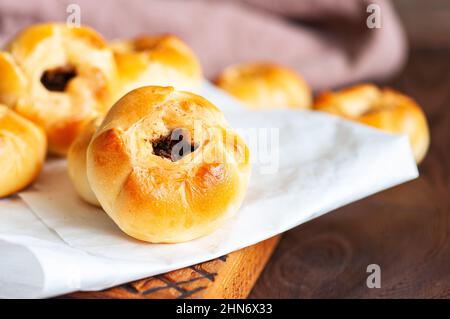 Torte a mano di carne al forno autentiche dell'Asia centrale - Belyash o samsa serviti su sfondo di legno. Primo piano. Foto Stock