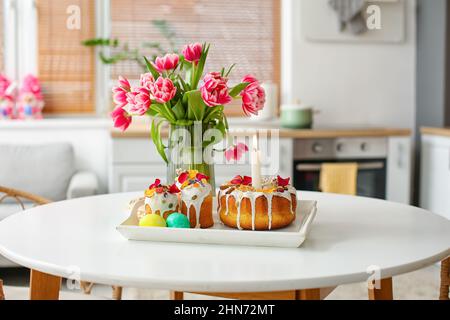 Vassoio con dolci di Pasqua, uova e vaso con tulipani sul tavolo da pranzo Foto Stock