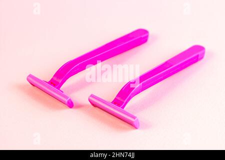Rasoio donna rosa usa e getta su sfondo pastello chiaro. Rimozione dei peli, procedura di epilazione e concetto di rasatura. Foto Stock