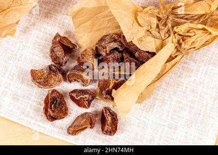 Tradizionale hoshigaki giapponese essiccato persimmon frutta snack fette in carta da imballaggio su sfondo chiaro vista dall'alto. Foto Stock