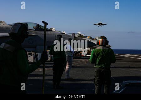 MAR DELLE FILIPPINE (Feb 13, 2022) i marinai della Marina degli Stati Uniti con la portaerei di classe Nimitz USS Abraham Lincoln (CVN 72) osservano le operazioni di volo a sostegno dell'esercizio 22 di Jungle Warfare (JWX 22) attraverso Okinawa, Giappone, il 13 febbraio 2022. JWX 22 è un esercizio di formazione sul campo su larga scala incentrato sull'utilizzo delle capacità integrate di partner congiunti e alleati per rafforzare la consapevolezza, le manovre e gli incendi di tutti i domini in un ambiente marittimo distribuito. (STATI UNITI Foto Navy di Sint. Di comunicazione di massa Seaman Aprentice Julia Brockman) Foto Stock