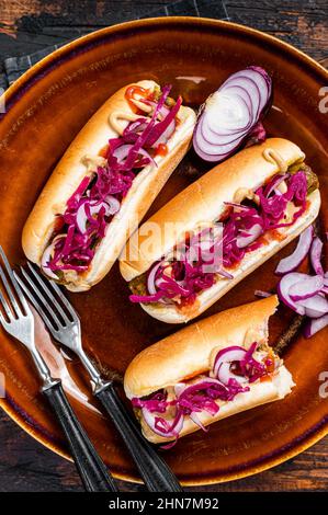 Cibo di strada - hot-dog Vegan con cavolo e salsiccia senza polpaccio. Sfondo di legno scuro. Vista dall'alto Foto Stock