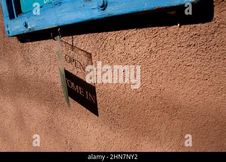 Un cartello aperto in plastica proietta un'ombra sul muro di una galleria d'arte a Santa Fe, New Mexico. Foto Stock