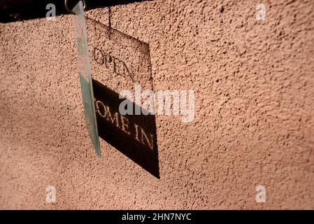 Un cartello aperto in plastica proietta un'ombra sul muro di una galleria d'arte a Santa Fe, New Mexico. Foto Stock