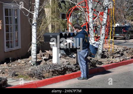 Un mailman americano o un corriere di lettere consegna la posta ad una fila di caselle postali a Santa Fe, New Mexico. Foto Stock