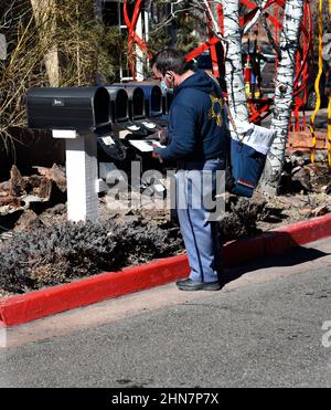 Un mailman americano o un corriere di lettere consegna la posta ad una fila di caselle postali a Santa Fe, New Mexico. Foto Stock